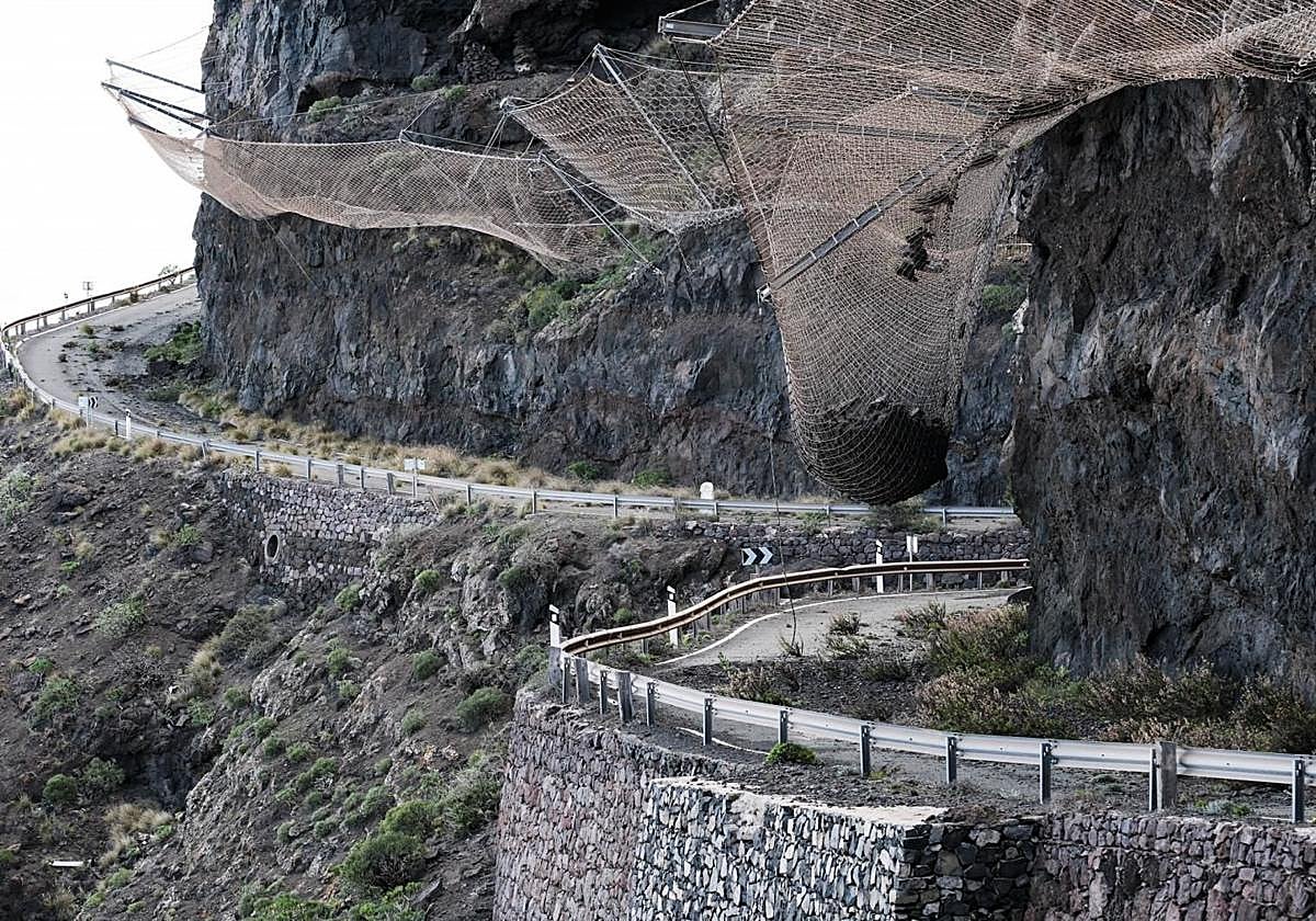 Vista parcial del tramo cerrado de la GC-200 donde se aprecia la bola de piedras suspendida en una malla de contención.