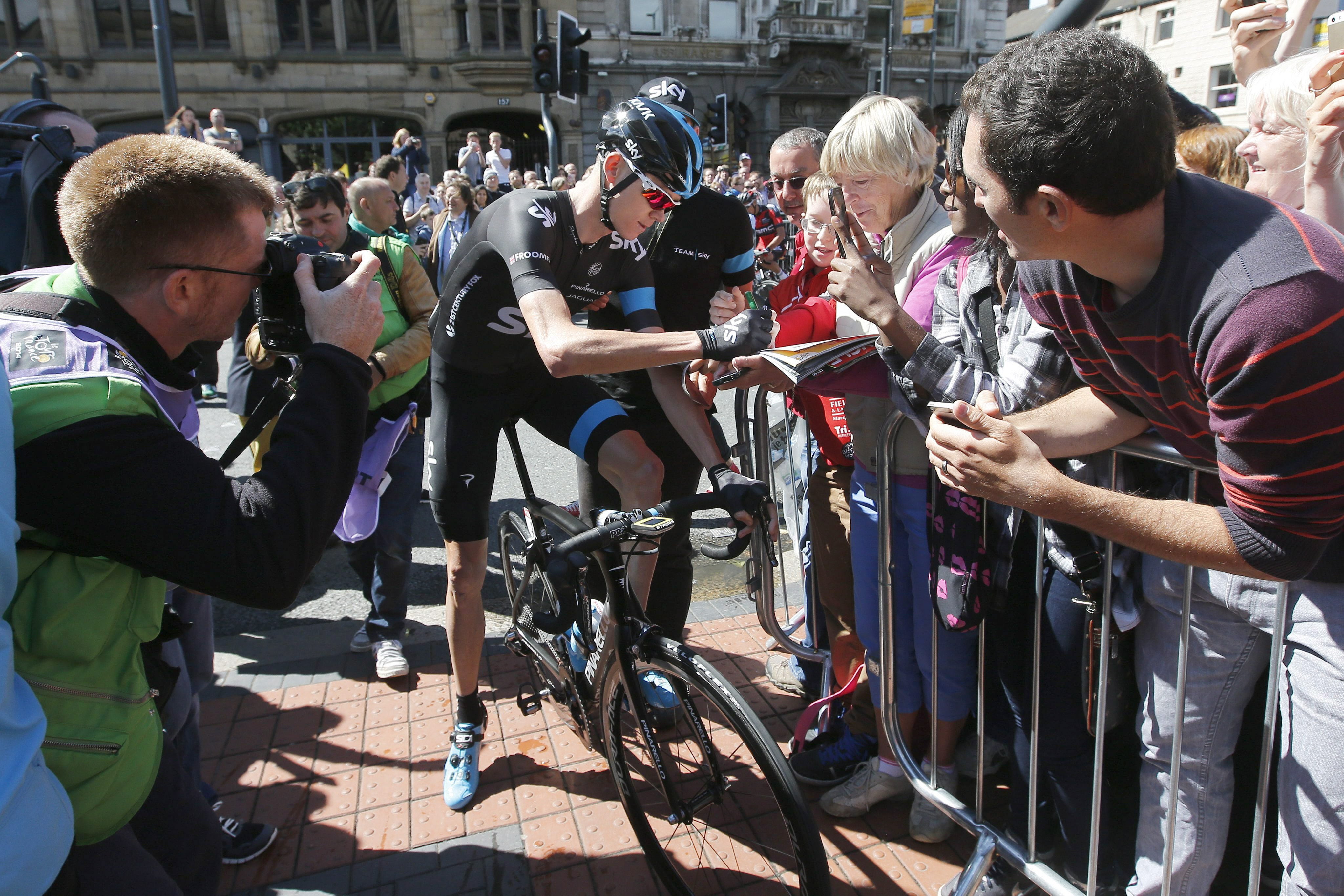 Chris Froome firma autógrafos antes de la salida.