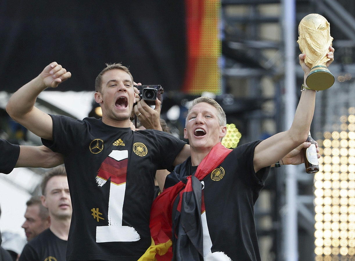 LA SELECCIÓN ALEMANA CELEBRA LA COPA DEL MUNDO CON MILES DE AFICIONADOS. Manuel Neuer (i) y Bastian Schweinsteiger celebran la Copa del Mundo con los aficionados durante la multitudinaria fiesta de bienvenida celebrada en su honor en la Puerta de Brandeburgo, en Berlín.