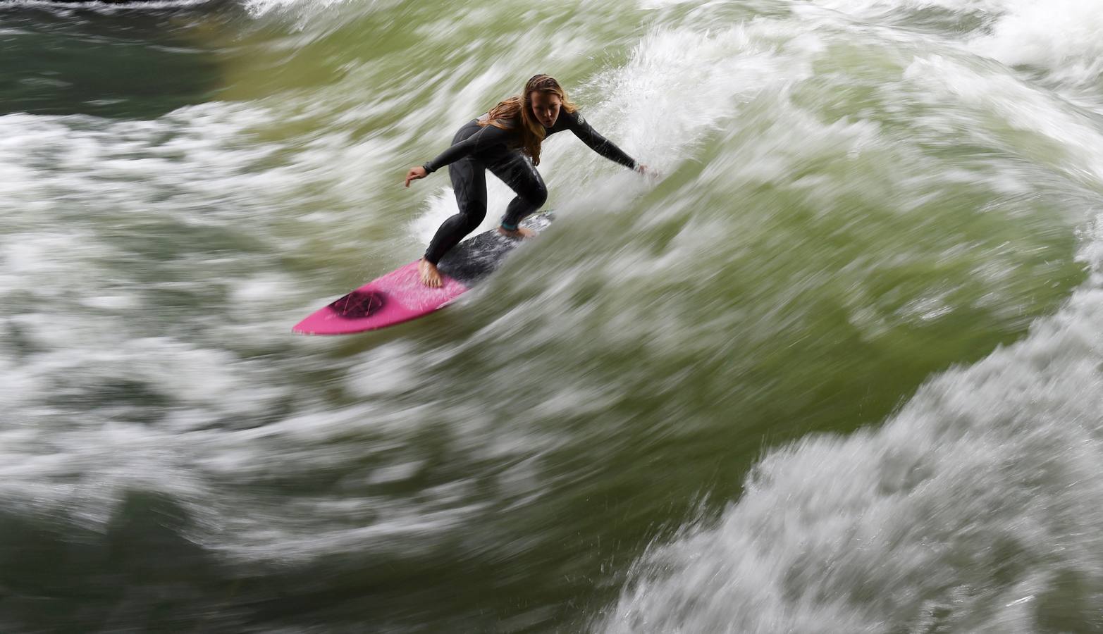 Jóvenes practican surf en el canal de Eisbach, al sur de Alemania