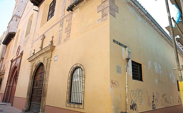 La parroquia de Santiago luce su fachada principal recién restaurada mientras el muro lateral aparece con pintadas, parcheados y cables. 