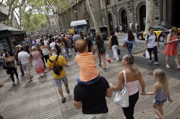 Una familia de turistas pasea, ayer, por Las Ramblas de Barcelona. :: a. estévez / efe