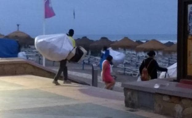 Uno de los manteros recoge sus artículos en dirección a la playa tras advertir presencia policial. 