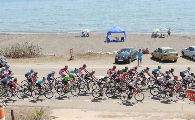 Imagen principal - En la imagen superior, el pelotón, al pasar por las playas de la Axarquía. A la izquierda, los ciclistas, en las inmediaciones de Antequera. Al lado, los corredores, en plena bajada por las carreteras malagueñas.