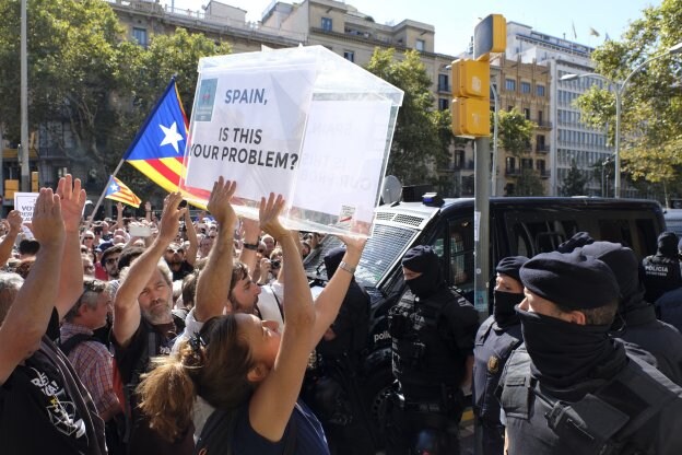 'España, ¿es este tu problema?' se lee en inglés en una urna que porta, ayer, una independentista frente a los Mossos d'Esquadra. 