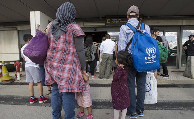 Refugiados sirios e iraquíes procedentes de Grecia hacen cola para recoger sus equipajes en Barajas, tras aterrizar en suelo español.