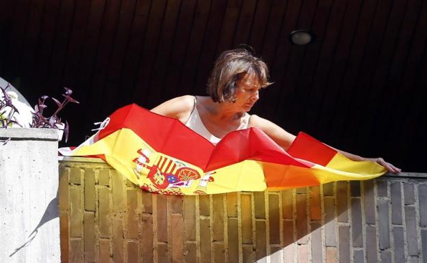 Una mujer coloca una bandera en su balcón 