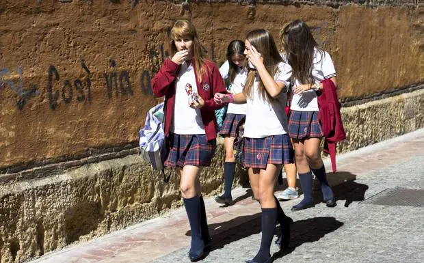Un grupo de niñas con uniforme escolar camina por una calle de León. 