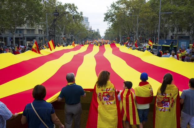 Participantes en la  manifestación de Barcelona despliegan una 'senyera'.  Abajo, incidentes entre los grupos ultras. :: efe / reuters