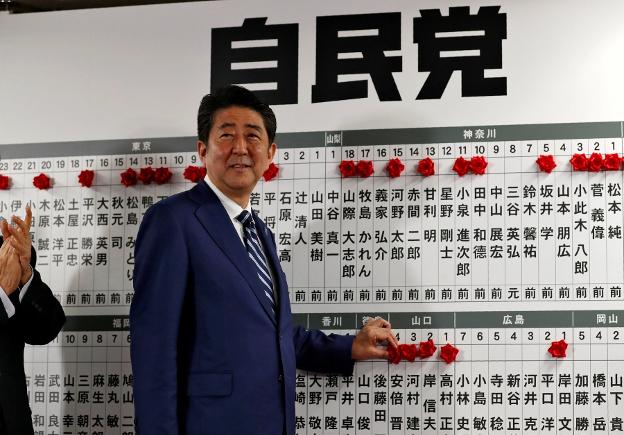 El primer ministro Shinzo Abe coloca una roseta junto a su nombre en la sede de su formación. :: reuters