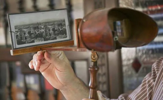 El coleccionista Juan Antonio Fernández Rivero sostiene un visor de madera para ver en 3D antiguas fotos en blanco y negro, como esta vista de Málaga en 1857.