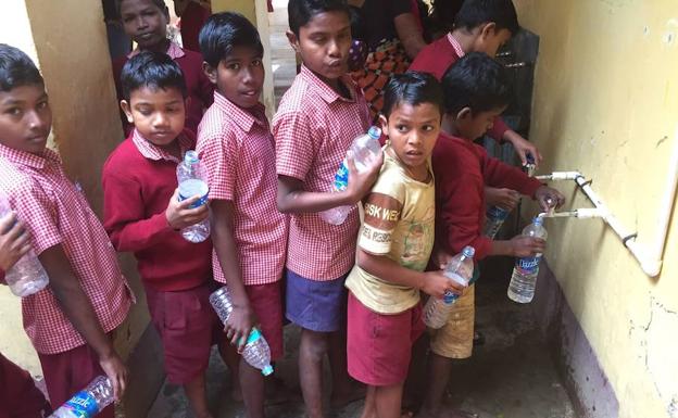 Alumnos de la escuela de Puri rellenan sus botellas de agua.