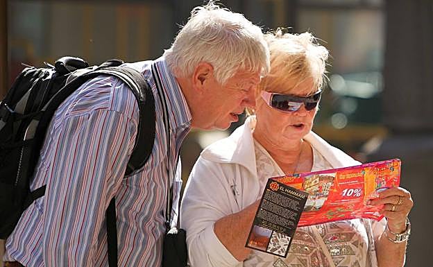 Una pareja de turistas revisa un plano de la ciudad de Málaga.