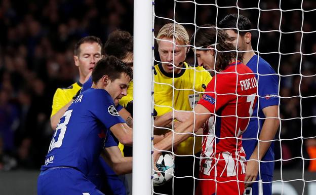 Azpilicueta y Filipe Luis pugnan por un balón con el colegiado como testigo.