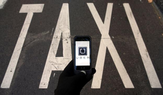 Una persona trata de abrir la aplicación digital de Uber en una parada de taxi.. :: s. pérez / reuters