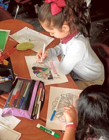 Imagen secundaria 2 - Arriba. Por el día de Andalucía, los niños y niñas visten los trajes típicos. Abajo. Niñas pintando abanicos y, a la izquierda, Pilar con otras alumnas y sus trabajos sobre Málaga. 