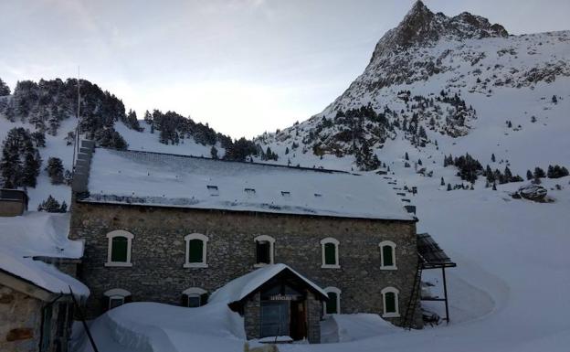 Imagen principal - Es el punto de partida para ascender al Aneto para miles de montañeros. Aquí, en La Renclusa, Antonio Lafón ha pasado 48 de sus 63 años de vida. Ansi Moslero y Rafael Quintero tras la barra del refugio Poqueira, en Sierra Nevada; a la derecha, Antonio Lafón a la puerta de La Renclusa, el lugar del Pirineo en el que ha transcurrido gran parte de su vida