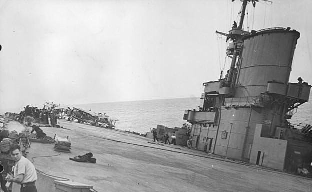 Imagen del hundimiento con el barco escorado y con los aviones todavía sobre su pista de despegue.
