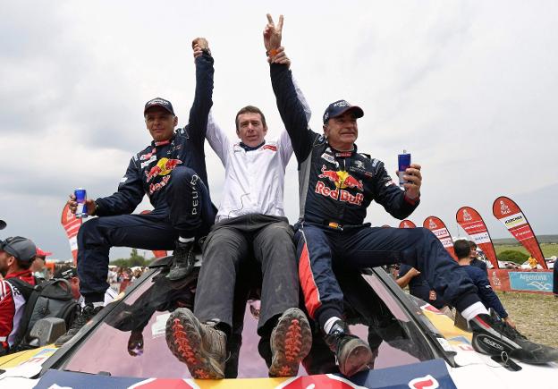Carlos Sainz, a la derecha, celebra el triunfo con su copiloto Lucas Cruz (i) y Bruno Famin (c), director del equipo Peugeot. :: FRANCK FIFE / afp