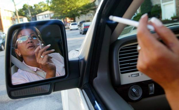 Imagen de archivo de una mujer fumando dentro de su coche.