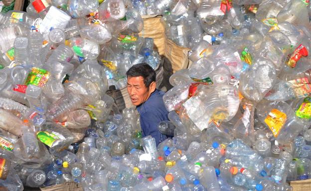 Un trabajador de una planta de tratamiento de residuos plásticos de Shenyang, al noreste de China, trata de abrirse paso entre un océano de envases.