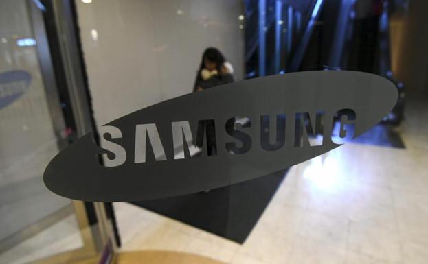 Una mujer camina junto al logo de Samsung.