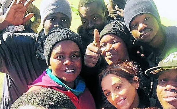 Helena Maleno hace el signo de la victoria rodeada de migrantes africanos. 