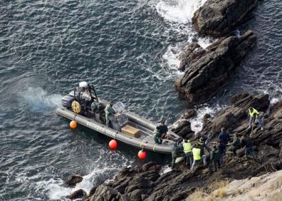 Imagen secundaria 1 - En busca de Paqui. En la foto de arriba, voluntarios participan en la batida en la playa de Salobreña. Abajo, a la izquierda, rescate del cuerpo en un acantilado.a la derecha, colgante geolocalizador.