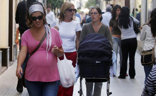 Una mujer embarazada pasea por una calle.
