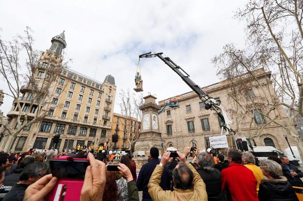 Arriba, la grúa retira la estatua. A la izquierda, los operarios amarran a Antonio López. 