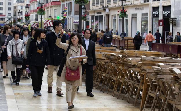 Un grupo de turistas asiáticos se sorprenden en su paseo por la calle Larios del montaje que se organiza para Semana Santa (archivo). 