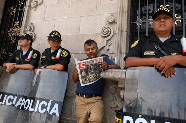 Un hombre lee el periódico en medio de un dispositivo de seguridad, ayer cerca del Palacio de Gobierno en Lima. :: Mariana Bazo / reuters