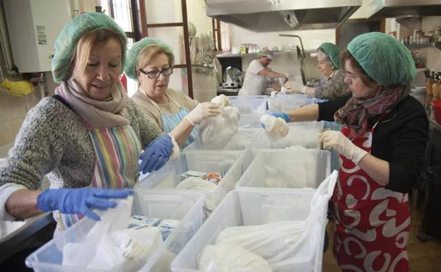 Algunas de las mujeres que colaboran con la asociación preparan bolsas con comida.