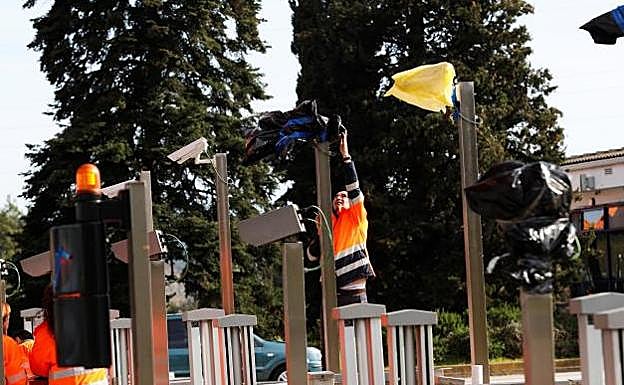 Operarios quitan las bolsas en las cámaras del peaje de la Ap-7 a la altura de La Roca del Vallès.