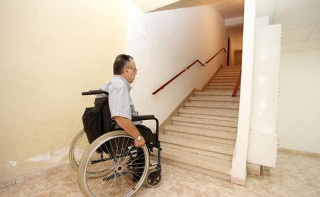 Imagen de archivo de un discapacitado mostrando la dificultad de subir las escaleras de su edificio.