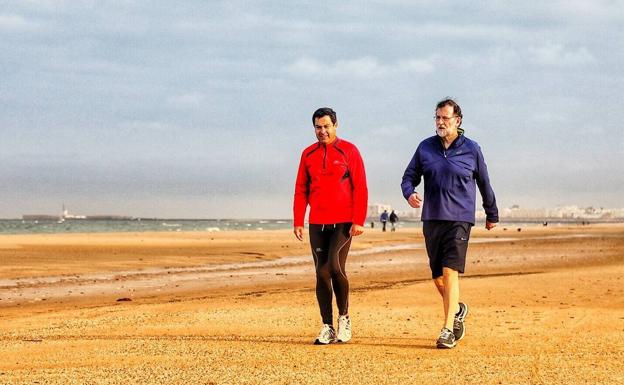 Mariano Rajoy y Juanma Moreno, en una caminata por la playa de Cádiz ayer.