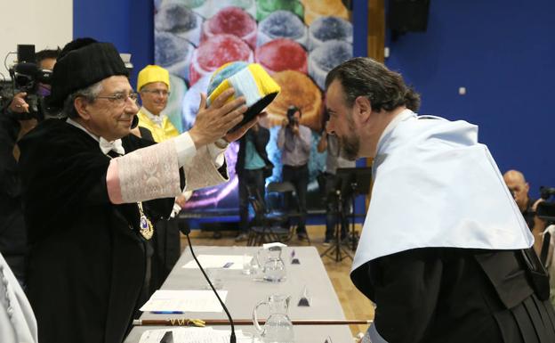 El rector impone a Carlos Álvarez un birrete bicolor que representa la unión de la Facultad de Filosofía y de Medicina. 