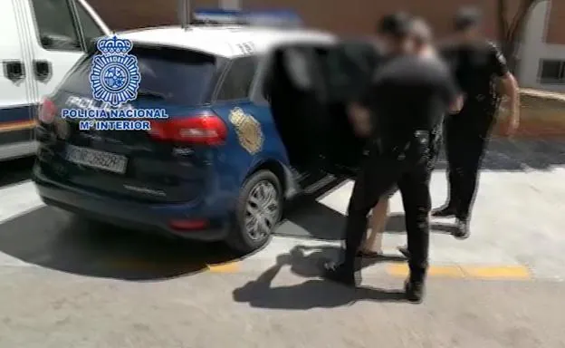 Dos agentes introducen al detenido en un vehículo polical.