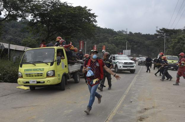 Voluntarios y bomberos evacúan una de la zonas próximas al volcán de Fuego. :: Johan ORDOñEZ / afp