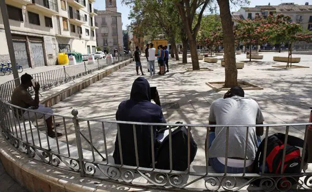 Un grupo de inmigrantes, sentados en una esquina de la Plaza de la Merced.