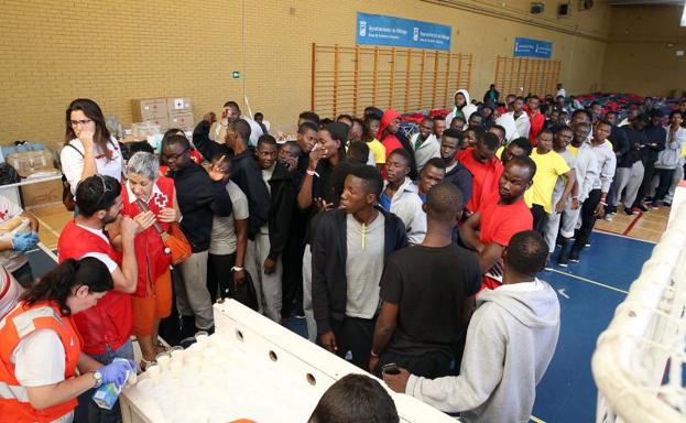 Inmigrantes hacen cola en el interior del polideportivo de Tiro Pichón para recibir un vaso de leche. 