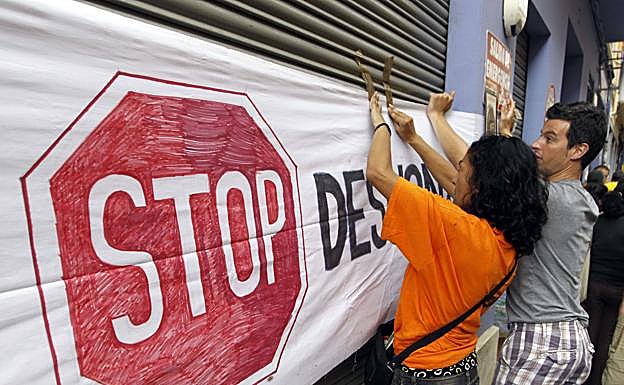 Miembros de la plataforma «Stop Desahucios» protestan con pancartas para intentar evitar el desalojo de una familia (archivo).