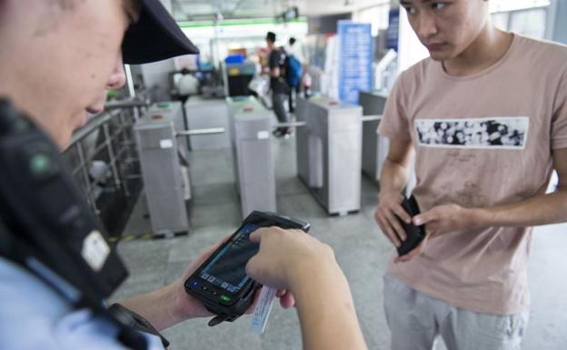 Un policía utiliza una PDA conectada a la base nacional para identificar a un joven en el metro de Shanghái.