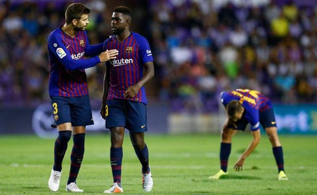 Piqué y Umtiti hablando durante el partido mientras Jordi Alba intenta tapar un agujero en el césped del José Zorrilla