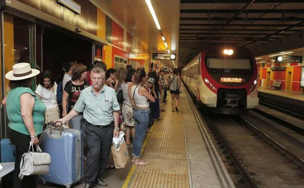 Viajeros esperan la llegada del Cercanías de la Costa en una estación. 