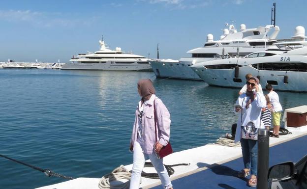 Turistas procedentes de Oriente paseando por uno de los muelles de Puerto Banús. 