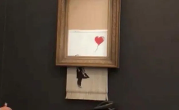 Momento en el que la obra de Banksy para por una trituradora de papel.
