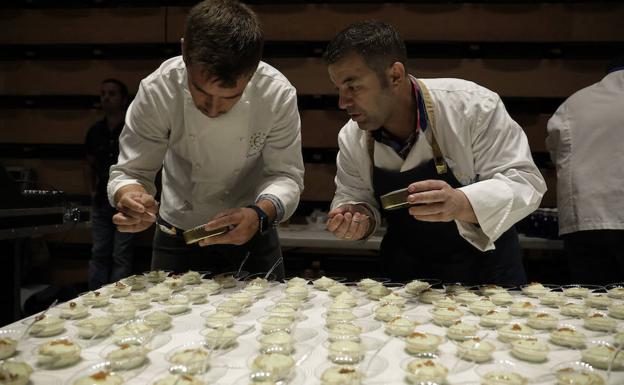 A la izquierda, dos chefs culminan una ensalada.