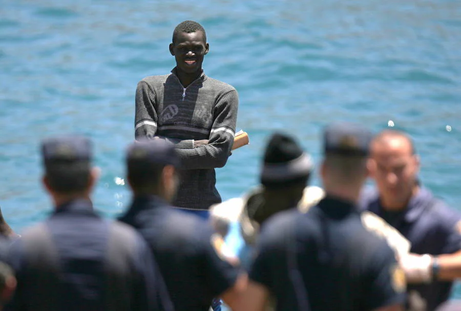 Un inmigrante africano se encuentra frente a policías españoles tras su llegada en un bote de pesca al Puerto de Los Cristianos, en Tenerife.