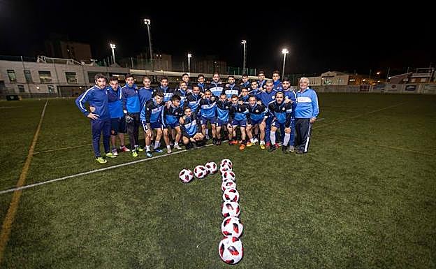 La plantilla de El Palo y el cuerpo técnico, junto a balones que dibujan un 'uno'.
